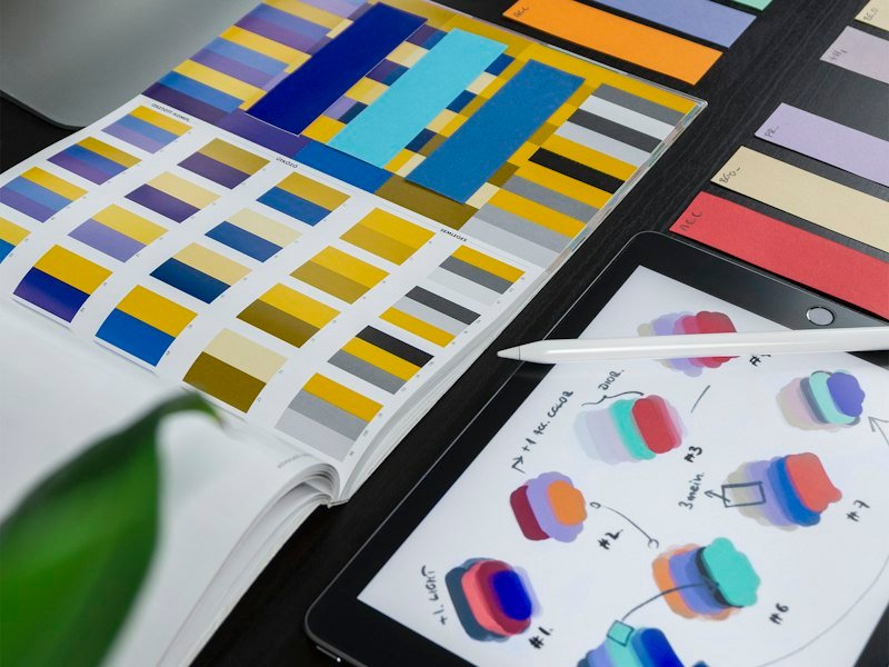 Designer working on logo sketches and color swatches at a desk
