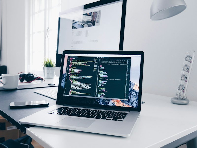 Laptop on a wooden desk showing website code in a text editor
