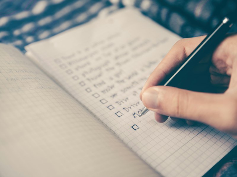 Open notebook with a handwritten checklist and pen on a desk