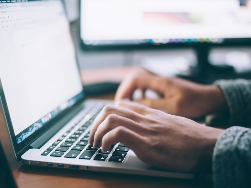 Person typing on a laptop while reviewing a landing page layout